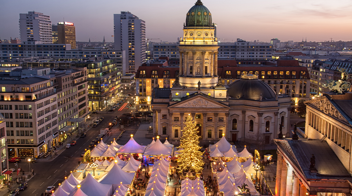Berlin city skyline with lit up Christmas tree and market stalls at night